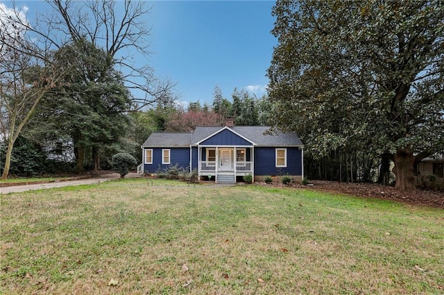 ranch-style house featuring covered porch, a shingled roof, a chimney, and a front yard