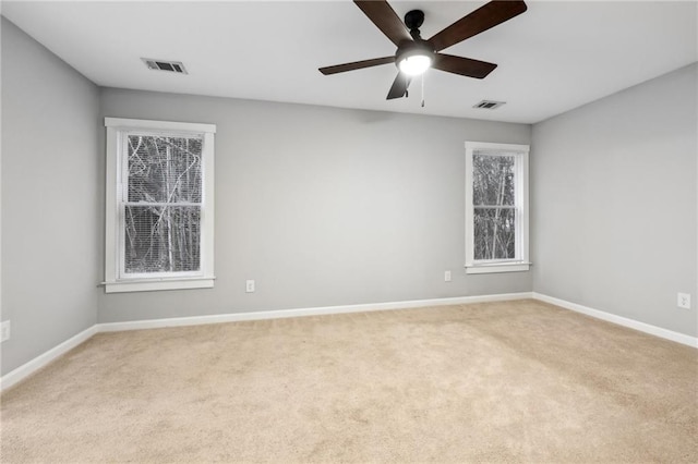 empty room with light carpet, baseboards, visible vents, and a ceiling fan