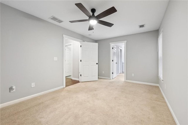 unfurnished bedroom featuring light carpet, ensuite bath, visible vents, and baseboards