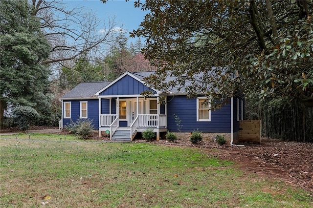 view of front of property with covered porch, roof with shingles, a front lawn, and board and batten siding