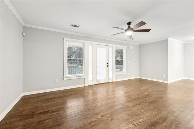 spare room featuring dark wood-style flooring, crown molding, visible vents, a ceiling fan, and baseboards