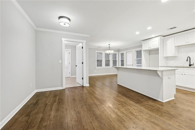 kitchen featuring visible vents, white cabinets, light stone counters, and a center island