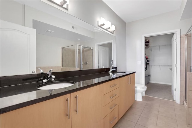 bathroom featuring tile patterned flooring, vanity, a shower with door, and toilet