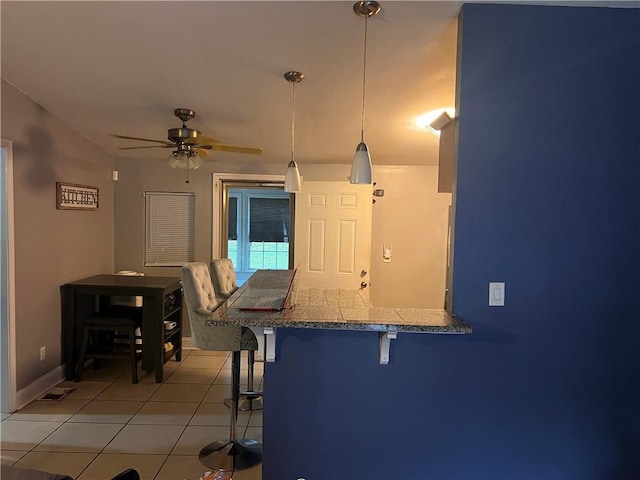 1506 Ravenel Rd, Conley, GA 30288 - kitchen with a breakfast bar, light tile patterned floors, decorative light fixtures, a ceiling fan, and a peninsula