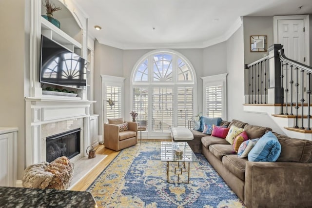 living room with hardwood / wood-style flooring, ornamental molding, and a fireplace