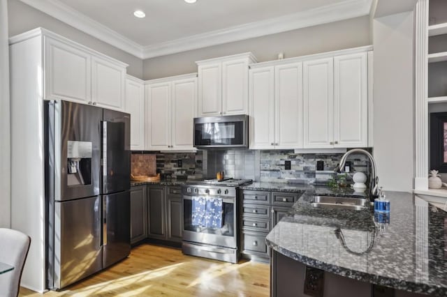 kitchen with white cabinetry, sink, dark stone countertops, ornamental molding, and stainless steel appliances