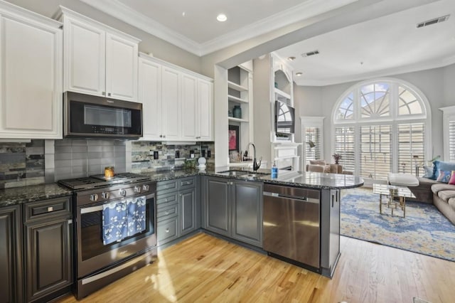 kitchen with white cabinetry, sink, dark stone counters, kitchen peninsula, and stainless steel appliances