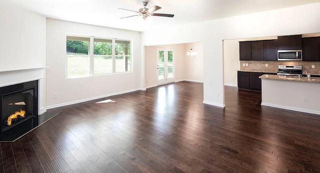 unfurnished living room featuring dark wood-type flooring, ceiling fan, and sink