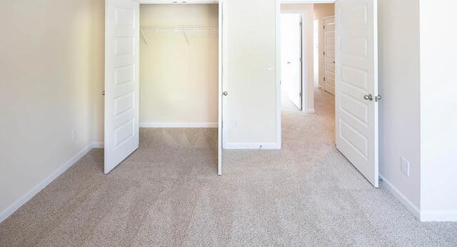 unfurnished bedroom featuring a closet and light carpet