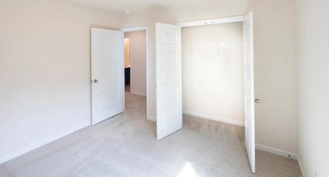 unfurnished bedroom with light carpet and a closet