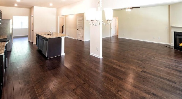 interior space featuring sink, appliances with stainless steel finishes, dark hardwood / wood-style floors, a center island with sink, and decorative light fixtures