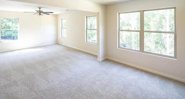 spare room featuring ceiling fan, a healthy amount of sunlight, and light carpet