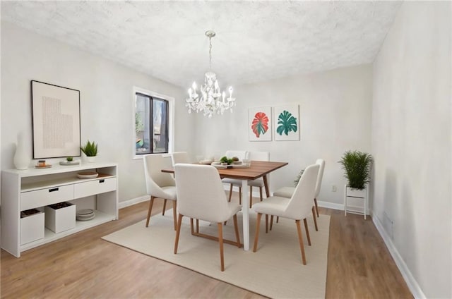 dining room with hardwood / wood-style floors, a textured ceiling, and a notable chandelier