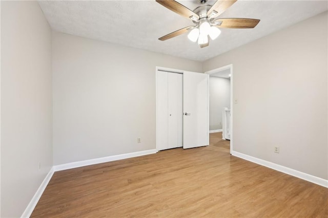 unfurnished bedroom featuring light wood-type flooring, ceiling fan, and a closet