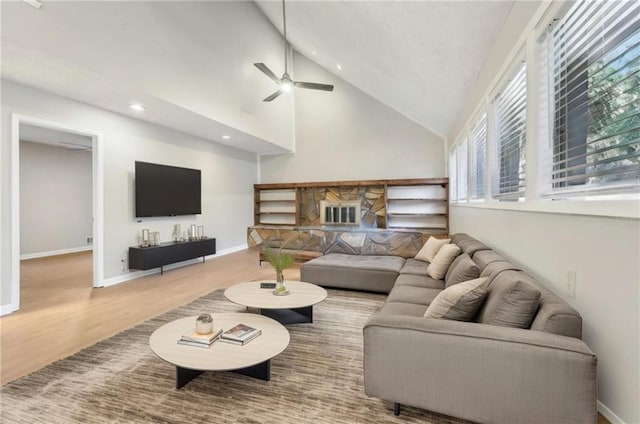 living room with hardwood / wood-style flooring, ceiling fan, and high vaulted ceiling