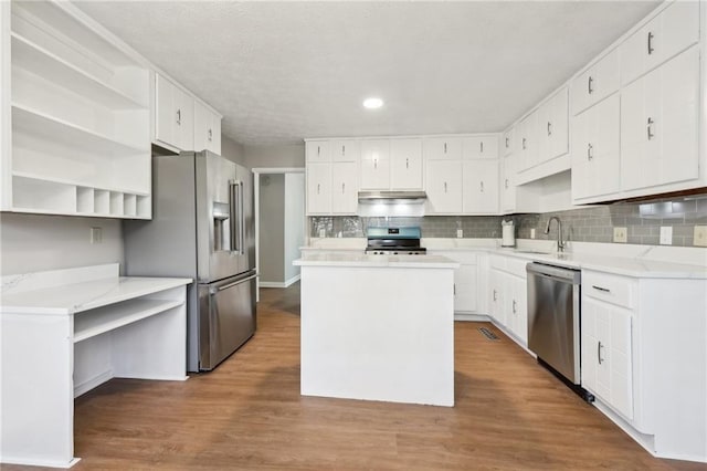 kitchen with appliances with stainless steel finishes, sink, a kitchen island, and white cabinets