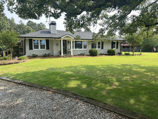 ranch-style home with a chimney, a front lawn, and roof with shingles
