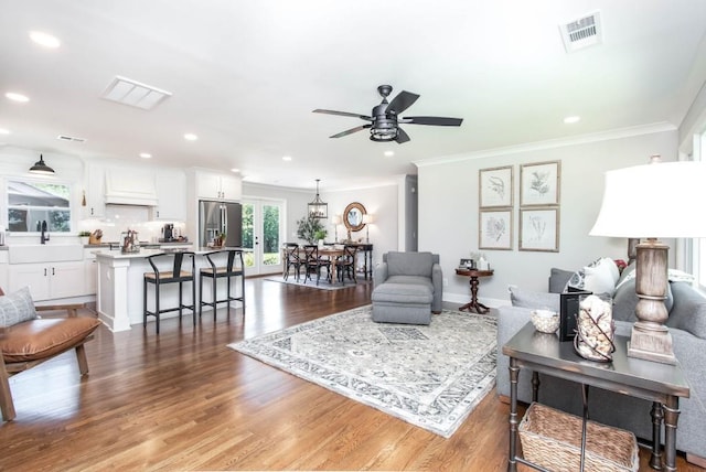 living area with crown molding, recessed lighting, a ceiling fan, wood finished floors, and baseboards
