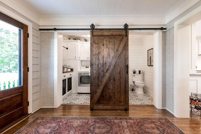 bathroom with washer / dryer, wood finished floors, toilet, crown molding, and wood walls