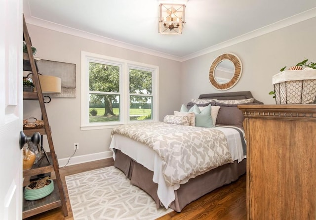 bedroom featuring ornamental molding, baseboards, wood finished floors, and a chandelier