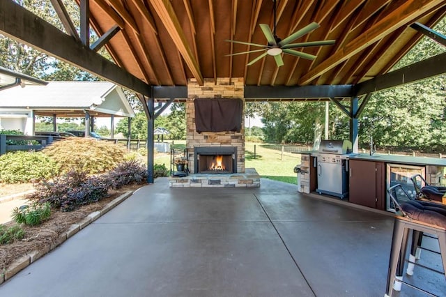 view of patio / terrace featuring an outdoor stone fireplace, a sink, ceiling fan, and wine cooler