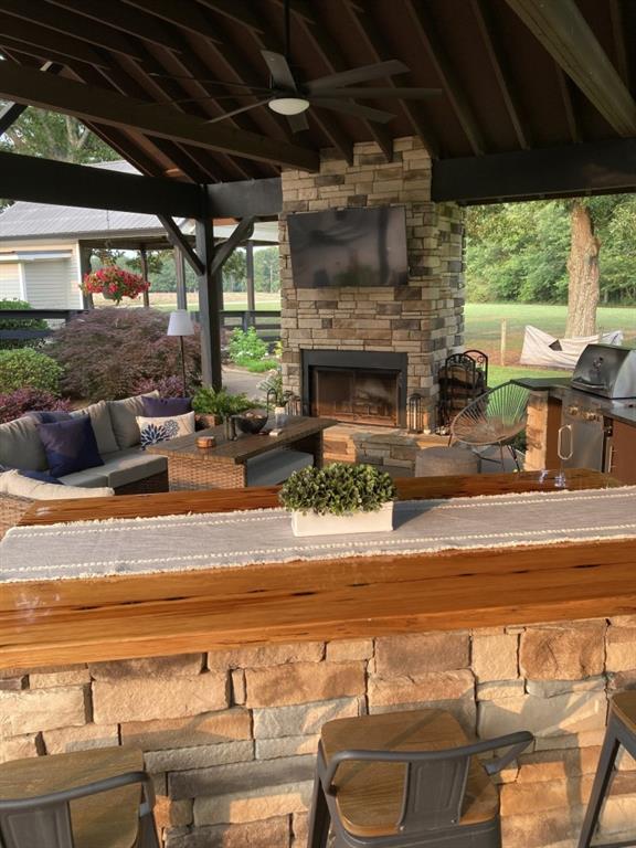 view of patio / terrace with an outdoor living space with a fireplace, a gazebo, a grill, and a ceiling fan