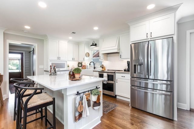 kitchen featuring stainless steel appliances, custom range hood, white cabinets, a kitchen island, and decorative backsplash