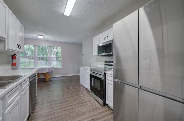 4975 Rockstone Way, Acworth, GA 30101 - kitchen featuring stainless steel appliances, light wood-type flooring, a textured ceiling, light countertops, and white cabinetry