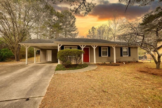 single story home with concrete driveway, an attached carport, and a front lawn