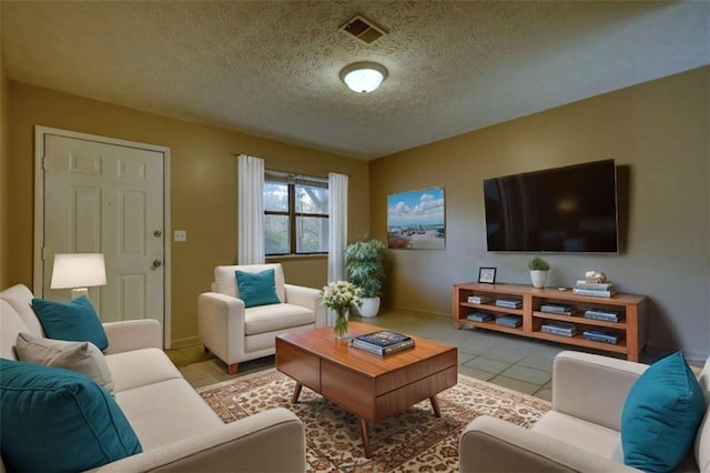 living area featuring a textured ceiling, baseboards, visible vents, and tile patterned floors