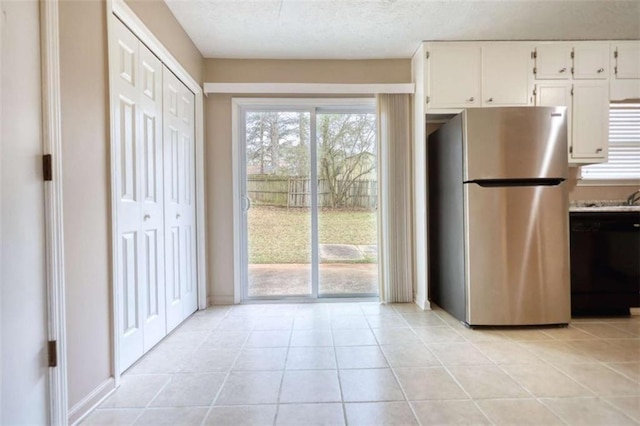 kitchen with light tile patterned flooring, white cabinets, light countertops, freestanding refrigerator, and dishwasher