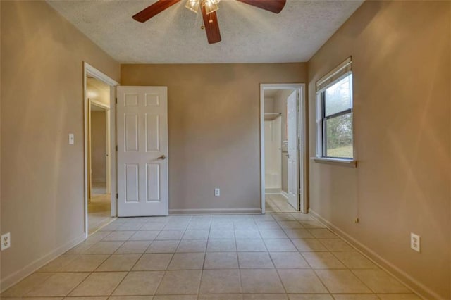 unfurnished bedroom with light tile patterned floors, a textured ceiling, and baseboards