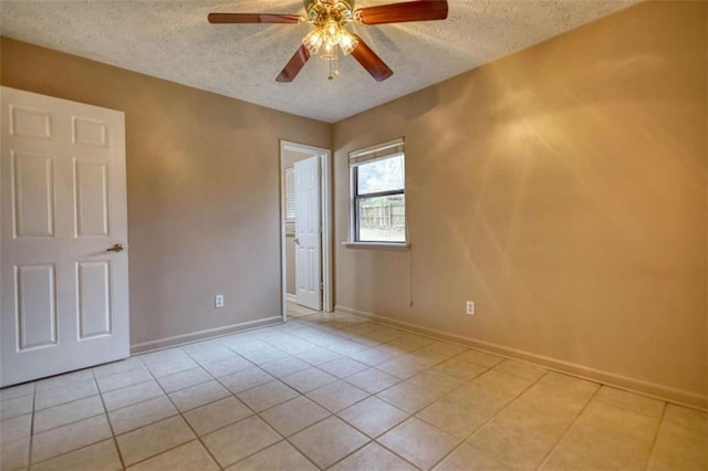 unfurnished room with light tile patterned floors, ceiling fan, baseboards, and a textured ceiling