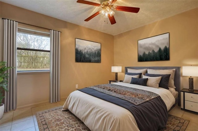 bedroom with a ceiling fan, a textured ceiling, baseboards, and light tile patterned floors