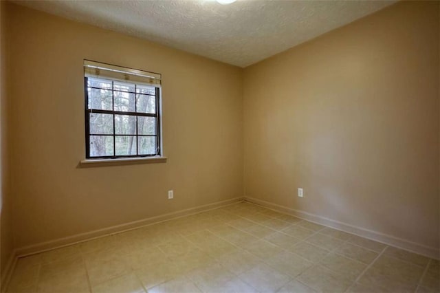 empty room featuring a textured ceiling and baseboards