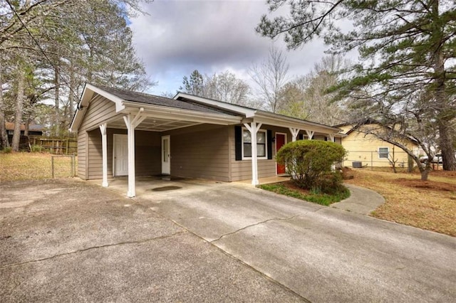 view of front of home featuring concrete driveway, a carport, and fence