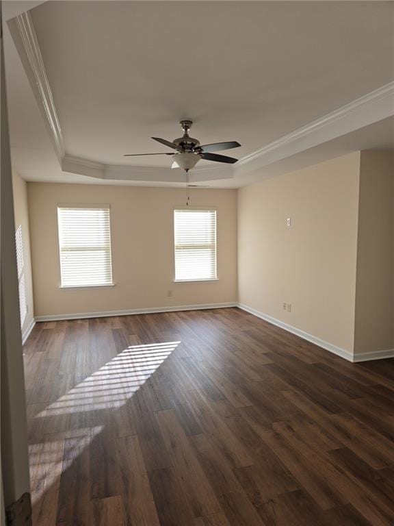 spare room with dark wood-type flooring, ceiling fan, ornamental molding, and a tray ceiling