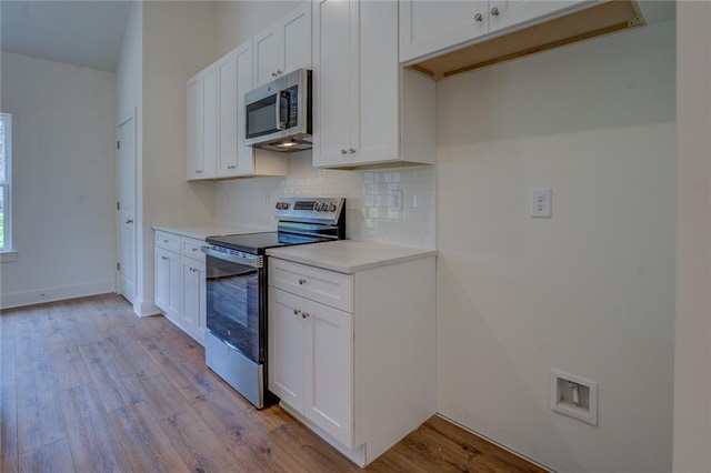 kitchen featuring stainless steel appliances, light countertops, decorative backsplash, light wood-style floors, and white cabinets