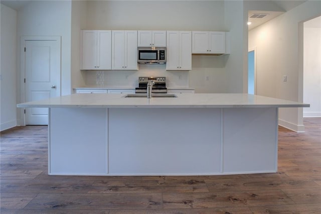 kitchen with stainless steel appliances, a sink, visible vents, white cabinets, and decorative backsplash