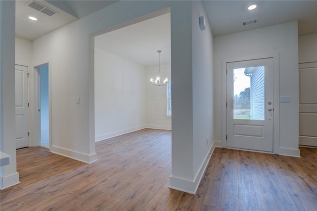 entrance foyer with a chandelier, baseboards, visible vents, and hardwood / wood-style floors