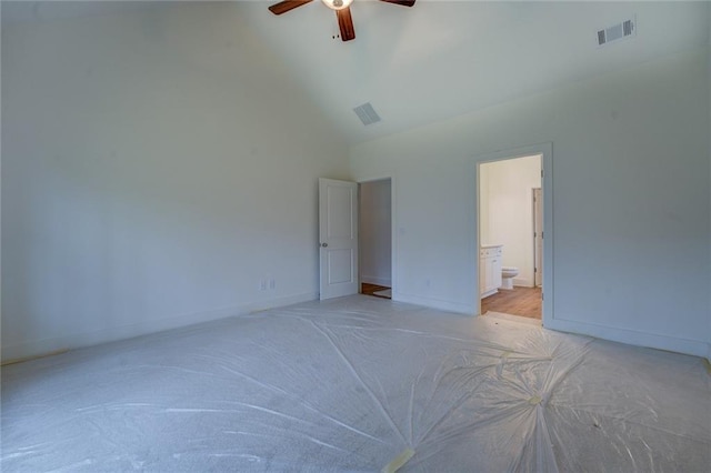 unfurnished bedroom with high vaulted ceiling, baseboards, visible vents, and ensuite bathroom