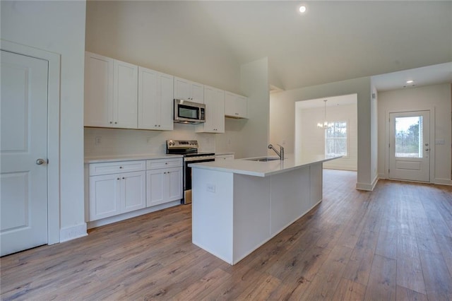 kitchen featuring stainless steel appliances, backsplash, white cabinetry, a sink, and light wood-type flooring