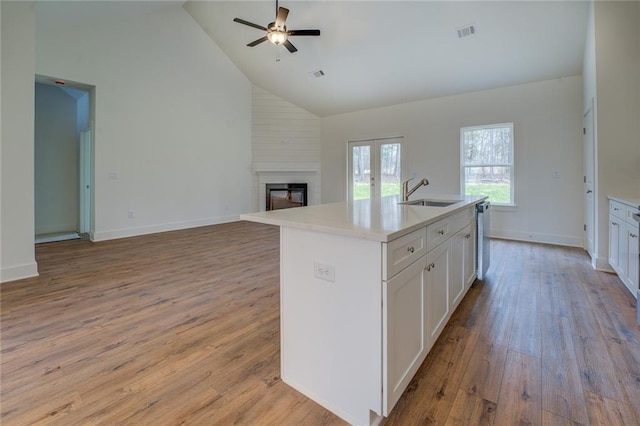 kitchen featuring visible vents, white cabinets, a sink, light wood-type flooring, and dishwasher