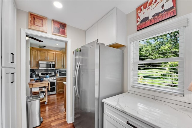 2176 Pine Lake Rd, Hiawassee, GA 30546 - kitchen with appliances with stainless steel finishes, tasteful backsplash, light wood-style flooring, light stone countertops, and white cabinets