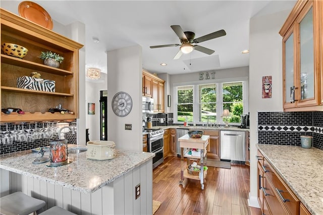 2176 Pine Lake Rd, Hiawassee, GA 30546 - kitchen featuring stainless steel appliances, decorative backsplash, light stone counters, ceiling fan, and wood finished floors