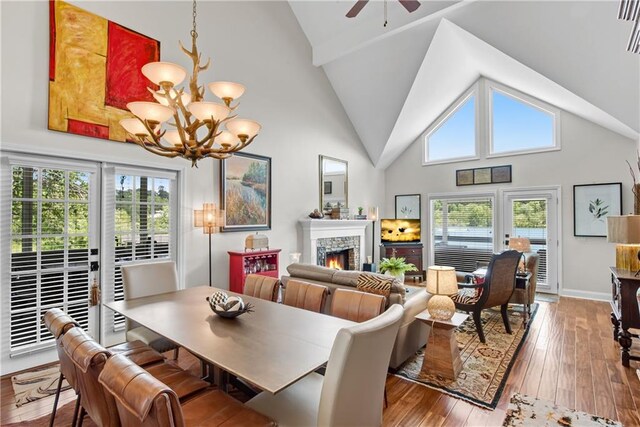 2176 Pine Lake Rd, Hiawassee, GA 30546 - dining space featuring a chandelier, wood-type flooring, a lit fireplace, ceiling fan, and high vaulted ceiling