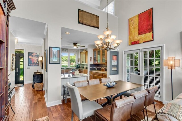 2176 Pine Lake Rd, Hiawassee, GA 30546 - dining space with a chandelier, healthy amount of natural light, wood-type flooring, a towering ceiling, and ornamental molding