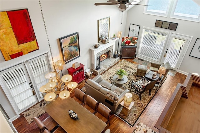 2176 Pine Lake Rd, Hiawassee, GA 30546 - living room featuring a high ceiling, a lit fireplace, hardwood / wood-style flooring, a ceiling fan, and baseboards