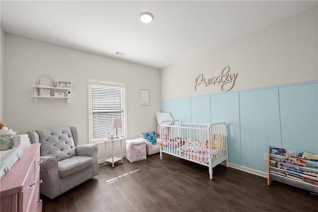 bedroom with a crib and dark hardwood / wood-style floors