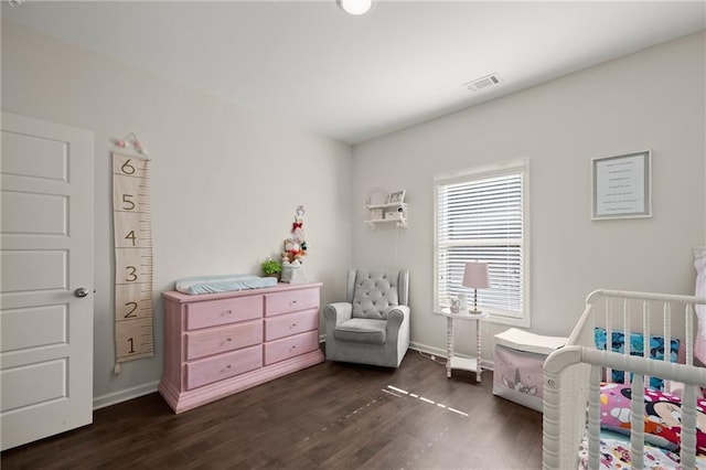 bedroom featuring dark hardwood / wood-style flooring and a nursery area